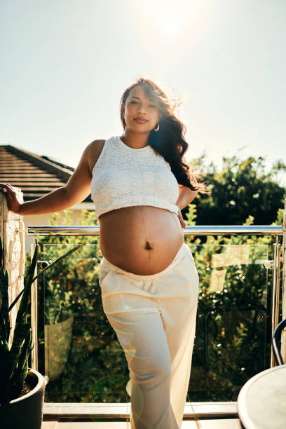 istock Pregnant Woman Standing on Sunny Balcony 2206504706