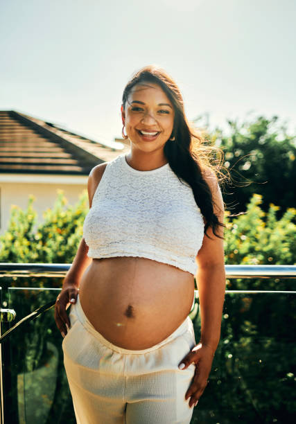 istock Pregnant Woman Standing on Sunny Balcony 2206504714
