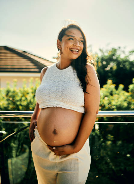 istock Pregnant Woman Standing on Sunny Balcony 2206504723