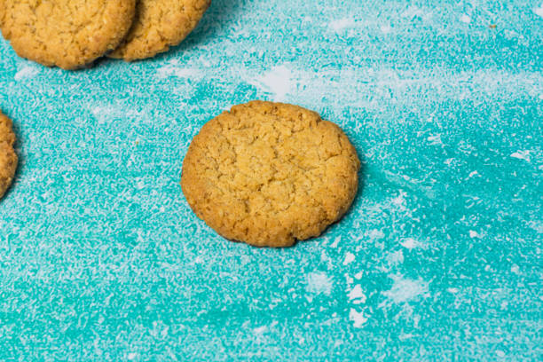 Round, golden-brown cookie rests on a blue surface. The contrast highlights its texture and warmth, evoking a sense of sweetness and indulgence. Perfect for dessert and snack-related themes.