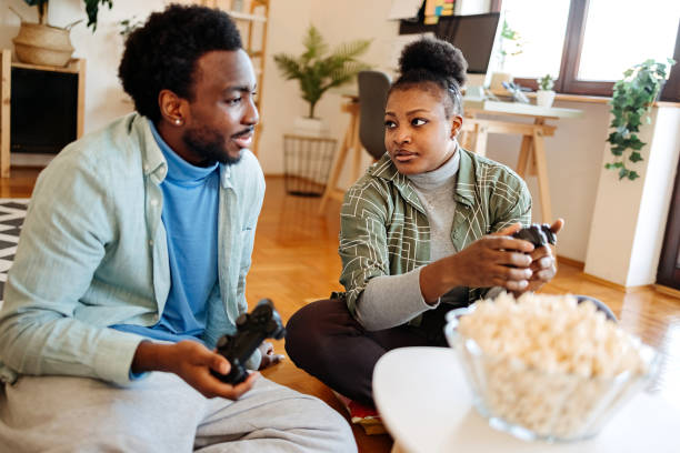 istock Young black couple having fun and enjoying playing video games at home using game controllers 2206508020