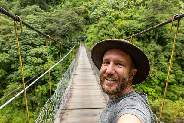 istock Man Taking Selfie on Suspension Bridge in Lush Forest 2206508841
