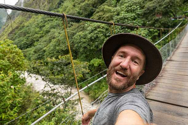 istock Man Taking a Selfie on a Suspension Bridge in Lush Forest 2206508843