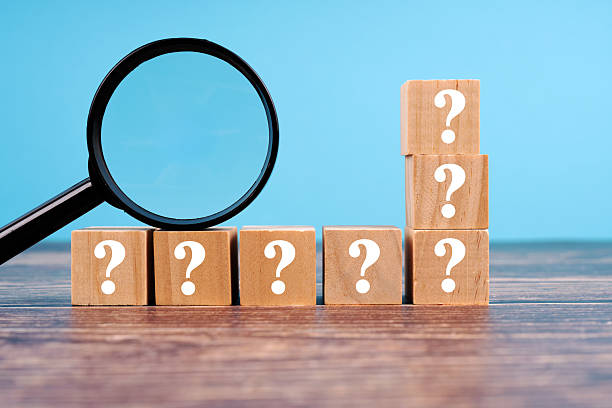 istock Question marks on wooden Blocks and magnifying glass on wooden table 2206510795