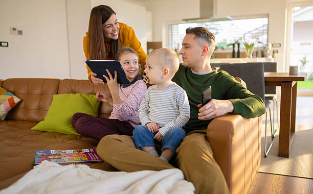 istock Young Family Sitting On Couch Absorbed In Digital Devices 2206514904