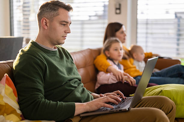 istock Young Family Sitting On Couch Absorbed In Digital Devices 2206515231