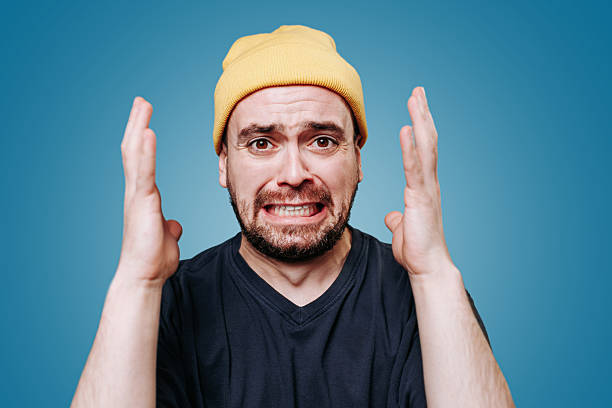 istock Man expressing frustration with hands raised against a blue background 2206515985