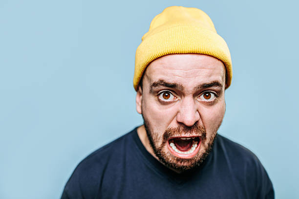 istock Man with yellow beanie expresses strong emotions against a blue background 2206516009