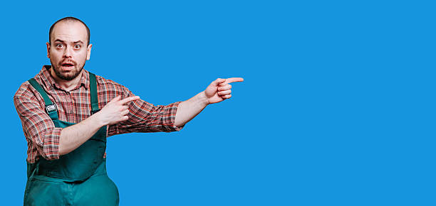 istock Man wearing green overalls points with excitement in a studio setting 2206518054