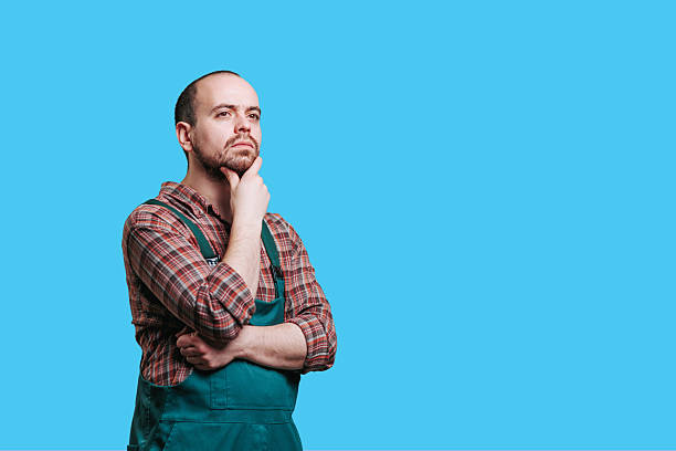 Man in apron pondering with a thoughtful expression against a blue background