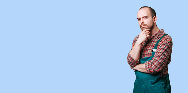 istock Thoughtful man in green apron pondering ideas against blue background 2206518059