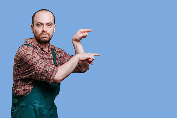 Man wearing overalls gestures expressively against a blue background