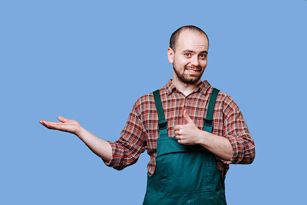 istock Person in green overalls making a positive gesture on blue 2206518095
