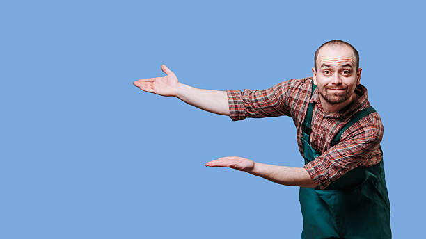 istock Man in apron gestures to showcase products against blue background 2206518112