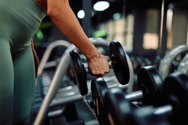 istock Woman picking up dumbbell in gym for weight training 2206518409