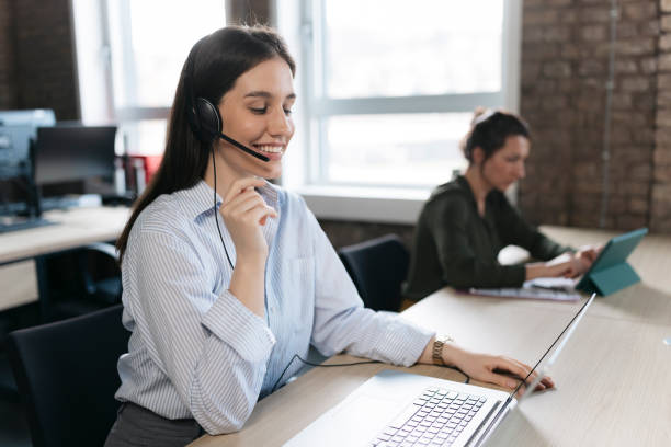 istock Smiling customer service representative assisting clients with headset and laptop 2206521834