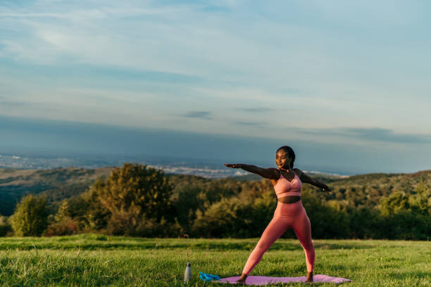 istock Young woman practicing yoga in warrior ii pose on a hilltop meadow 2206521989