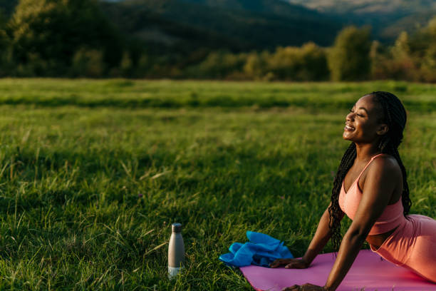 istock Young woman practicing cobra pose on yoga mat in nature 2206522051