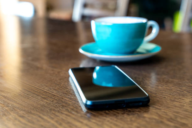 Scene of daily life with smartphone and vibrant turquoise coffee cup placed on wooden surface, capturing casual home moment