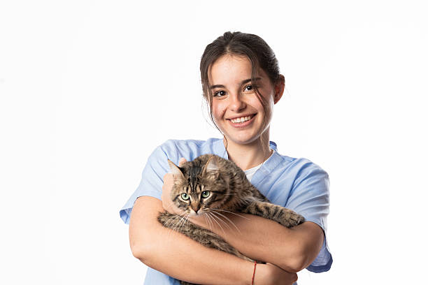 Young veterinarian holding a tabby cat and smiling at the camera, isolated on white background