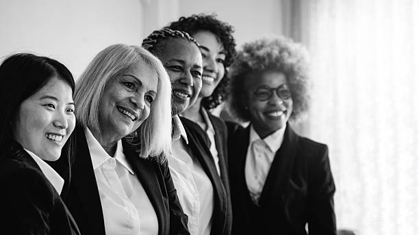 Multi Generation business women having fun together at work inside bank office. Finance, teamwork and corporate concept. Black and white editing