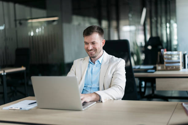 istock Smiling businessman working on laptop in modern office 2206525425