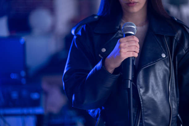 istock Female singer with microphone performing rock music on the stage 2206534676