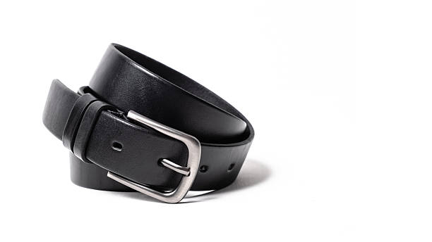 Twisted black leather belt with matted metal buckle isolated on white background. Fastened fashionable unisex, man or woman accessory for trousers, jeans, dress. Male luxury strap. Haberdashery goods
