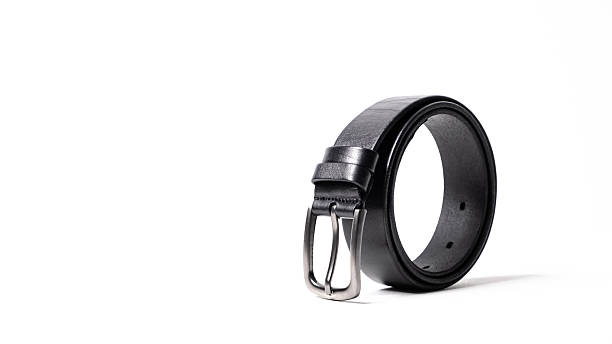 istock Twisted black leather belt with matted metal buckle isolated on white background. Fastened fashionable unisex, man or woman accessory for trousers, jeans, dress. Male luxury strap. Haberdashery goods 2206536694