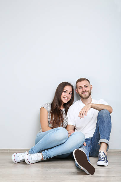 istock Happy young couple sitting on the floor on grey background 2206537309