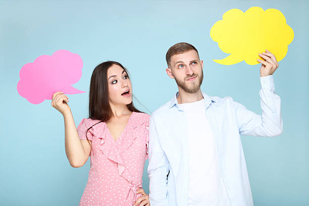 istock Happy young couple with paper speech bubbles on blue background 2206538060