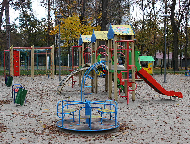 istock Sand covered with leaves on the empty multi-colored playground with slides and small merry go round in Kyiv city 2206538547