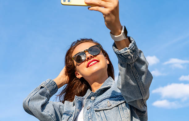 istock Young brunette woman wearing sunglasses taking selfie using her mobile phone. 2206538644