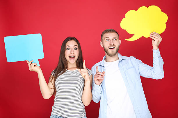 istock Happy young couple with paper speech bubbles on red background 2206541038