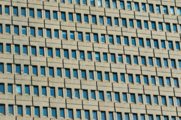 Close-up of a building's facade with many identical windows in a regular grid pattern. The building's material is light brown in Manchester, UK.