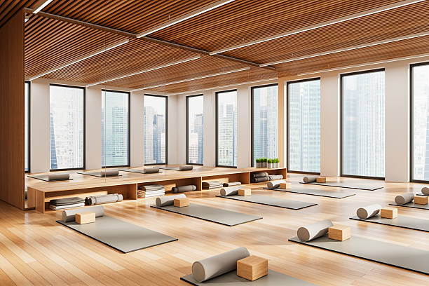 Yoga studio with mats, bolsters, and blocks on wooden floor, modern style, city view background. Concept of urban wellness. 3D Rendering