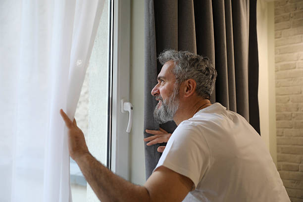 istock Smiling Man with Gray Hair and Beard Looking Through the Window 2206552155
