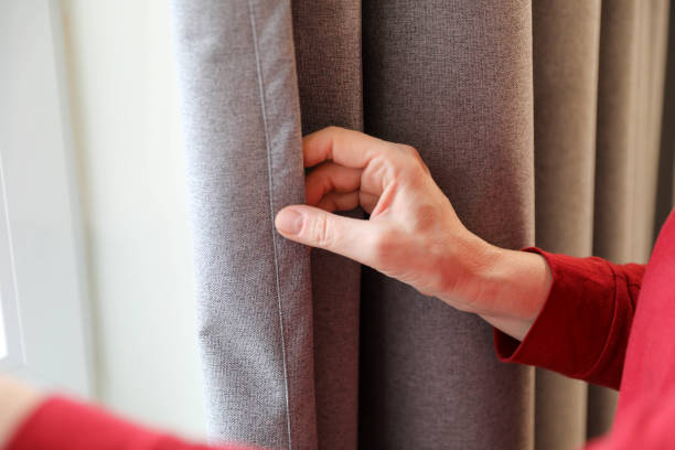 istock A woman's hand moves the curtain up close. 2206552237