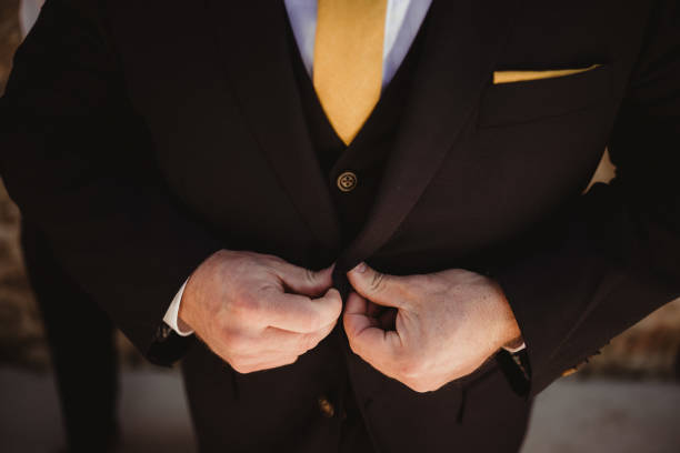 istock Man buttoning up suit jacket with bright yellow tie 2206557387
