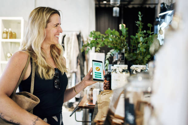 Woman showing payment confirmation on phone to cashier in boutique store stock photo
