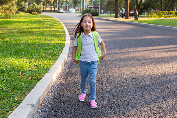istock Happy young girl walking to school with backpack in park setting 2206559139