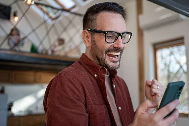istock Excited man celebrating success on smartphone at home 2206559956