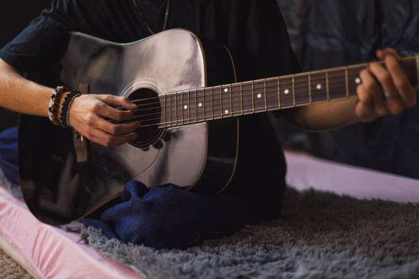 istock Young man playing a guitar at home 2206575295