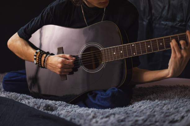 istock Young man playing a guitar at home 2206575296