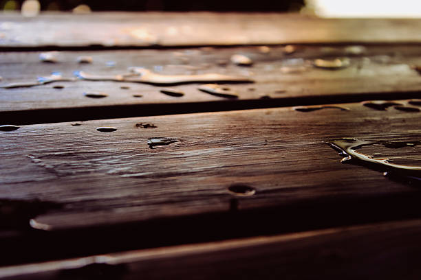 low angle view of water droplets and pooling on sealed wood decking boards or table plank boards for furniture. exterior decor background