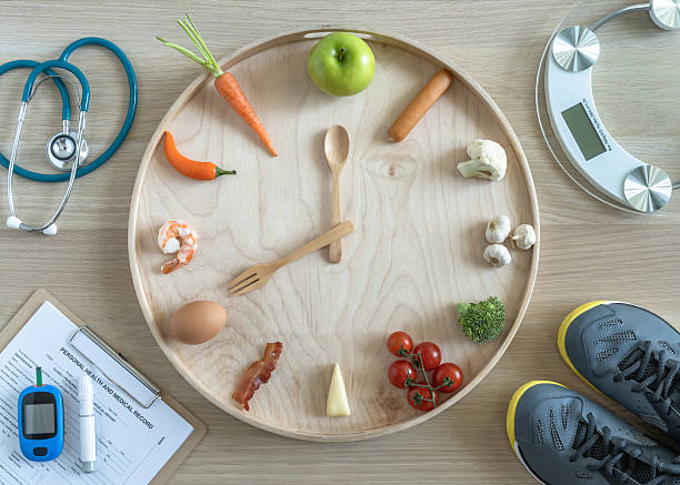 istock Intermittent fasting IF and keto diet concept with hour clock timer for skipping meal, eating ketogenic food low carb, high fat food meal healthy nutritional dish with gym exercise for weight loss 2206577052