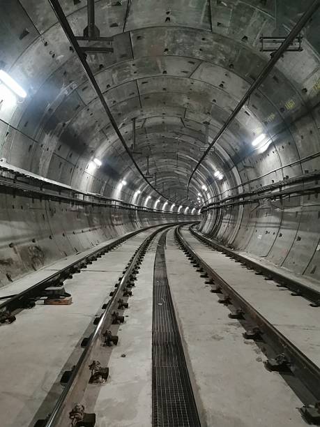 istock Illuminated underground train tunnel with curved tracks turning right. Empty, no trains or people. Industrial infrastructure with cables and lighting. A perspective view of modern subway construction 2206580598