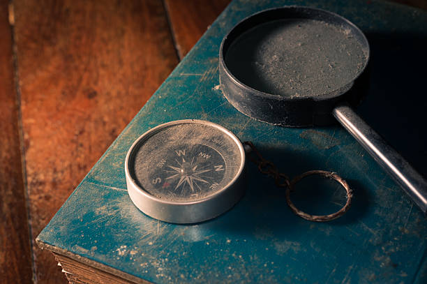 istock Old compass with magnifying glass on vintage book. 2206585016