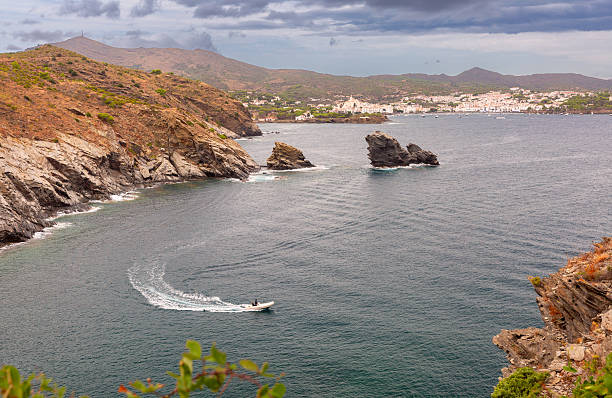 View of Cadaques bay with rocky coastline, rock formations, and a boat in Catalonia, Spain