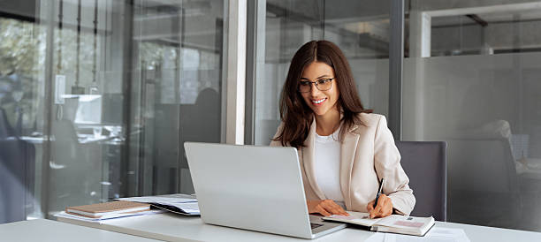 istock Middle age woman using laptop computer for business studying, having videocall with online virtual webinar training meeting, writing notes. Focused businesswoman working in office. Banner, copy space 2206586886
